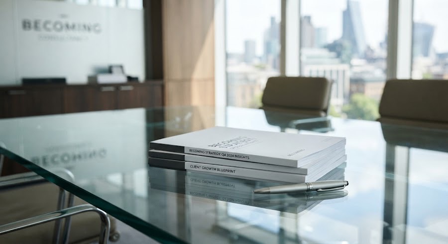 A stack of reports on a glass table in a bright office
